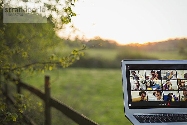 Video-Chat mit Freunden auf Laptop-Bildschirm am ländlichen Zaun