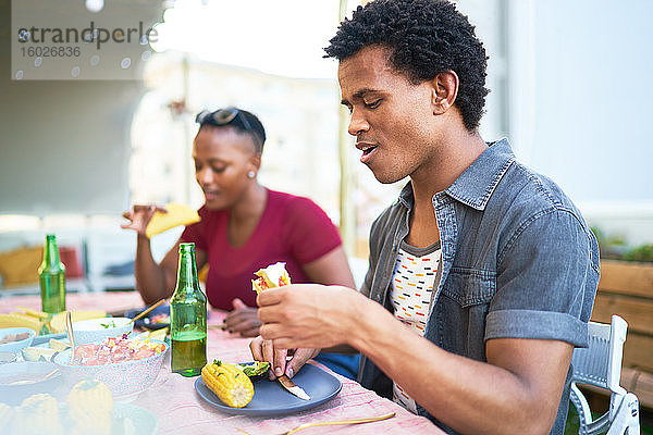 Junger Mann isst Taco-Mittagessen am Terrassentisch