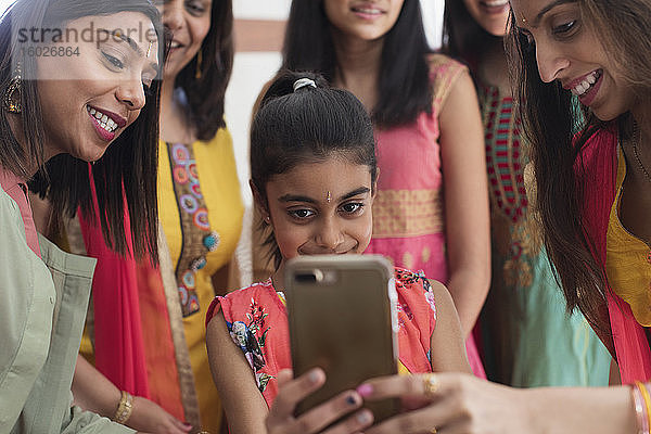 Indische Frauen und Mädchen in Saris und Bindis mit Smartphone