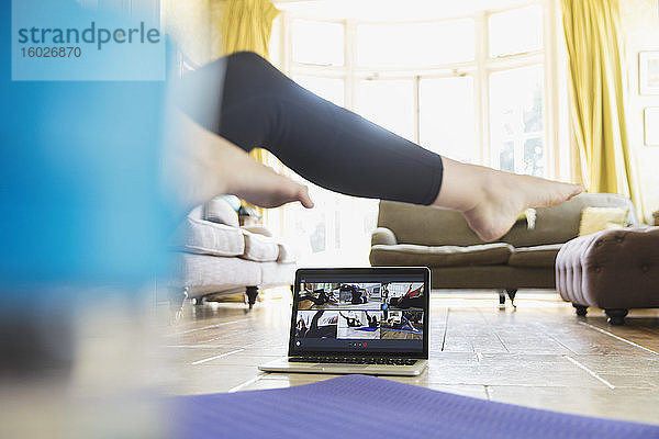 Frau übt online mit Laptop im Wohnzimmer