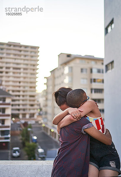 Glückliches junges Paar umarmt sich auf städtischem Balkon