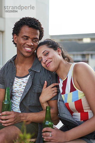 Glückliche junge Freunde trinken Bier auf der Terrasse