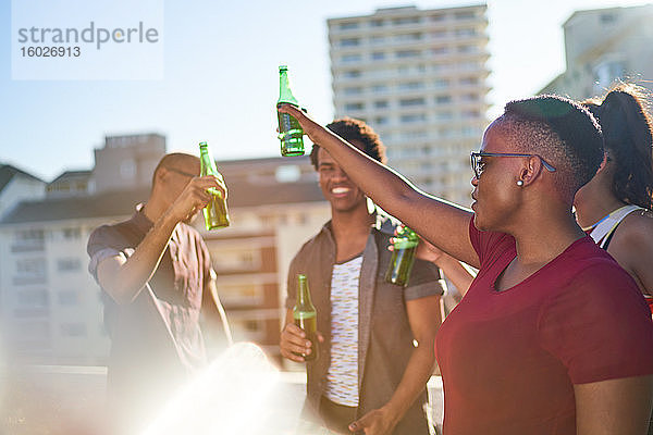 Sorgenfreie junge Freunde trinken Bier auf dem sonnigen Stadtbalkon