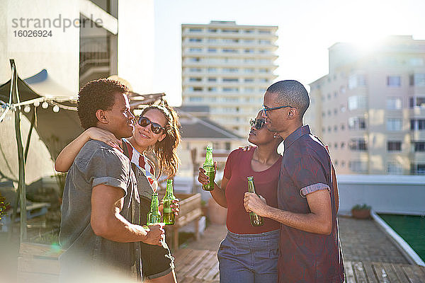 Junges befreundetes Paar trinkt Bier auf dem sonnigen Dachbalkon der Stadt