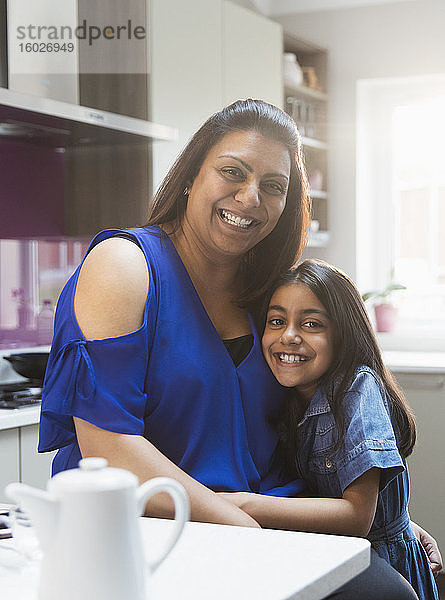Porträt einer glücklichen Mutter und Tochter  die sich in der Küche umarmen