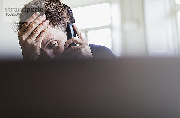 Müde Frau telefoniert am Laptop