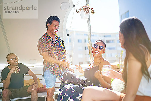 Glückliche junge Freunde hängen auf dem sonnigen Dach der Stadt herum