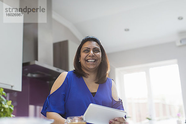 Portrait einer glücklichen Frau mit digitalem Tablett in der Küche