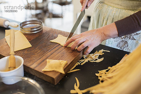 Nahaufnahme einer Frau  die frische hausgemachte Pasta schneidet
