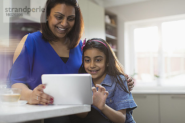 Glückliche Mutter und Tochter benutzen digitales Tablett in der Küche