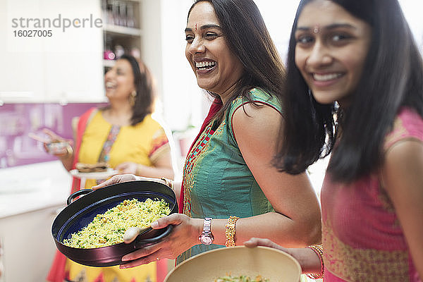 Glückliche indische Frauen in Saris kochen Essen in der Küche