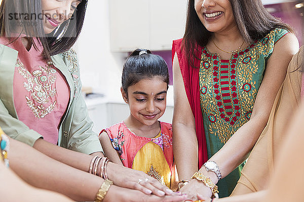 Indische Frauen und Mädchen in Saris reichen sich die Hände