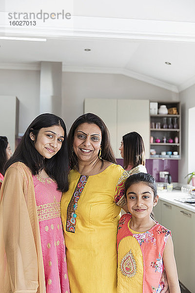 Portrait glückliche indische Mutter und Töchter in Saris in der Küche