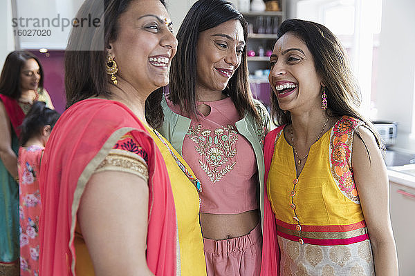 Glückliche indische Schwestern in Saris lachen in der Küche