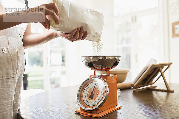 Frau misst Mehl zum Backen in der Küche