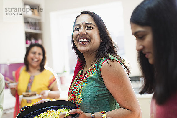 Glückliche indische Frau in Sari bereitet mit der Familie in der Küche Essen zu