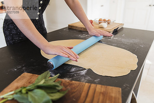 Teenager-Mädchen rollt Teig auf der Küchentheke aus