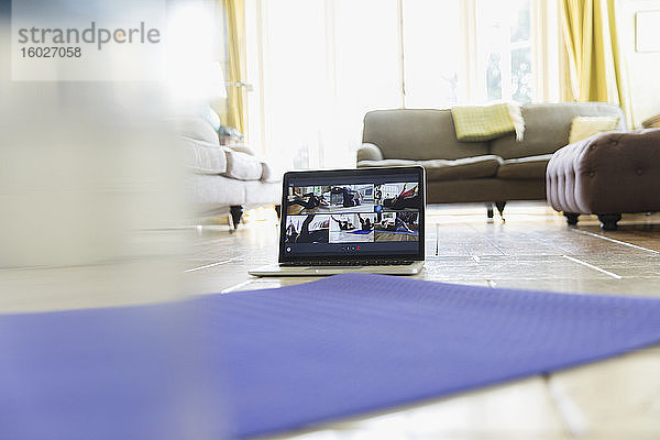 Übungsklassen-Streaming auf Laptop-Bildschirm hinter der Yogamatte