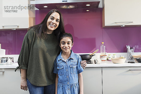 Porträt einer glücklichen indischen Mutter und Tochter beim Kochen in der Küche