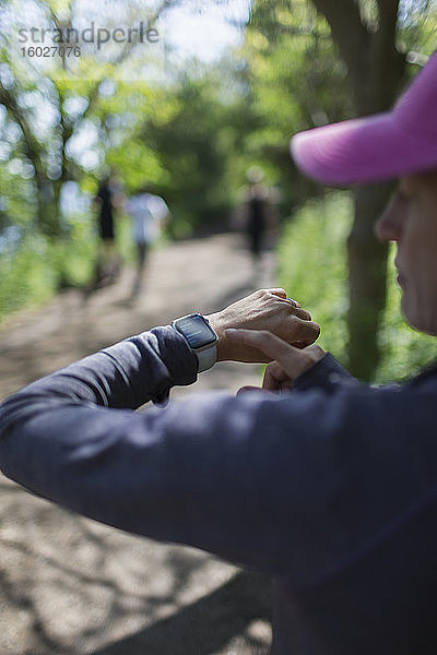 Frau mit Smartphone joggt auf einem Pfad im Park