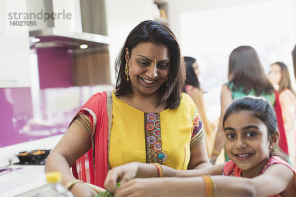 Indische Mutter und Tochter in Saris kochen Essen in der Küche