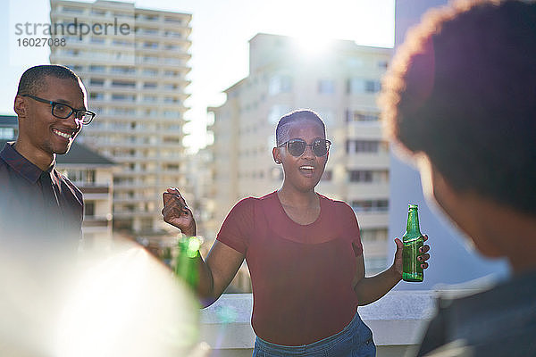 Unbeschwerte junge Freunde tanzen und trinken Bier auf dem sonnigen Dach
