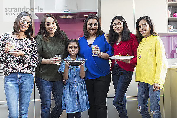 Porträt glücklicher indischer Frauen und Mädchen  die in der Küche Essen zubereiten