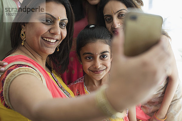 Glückliche indische Frauen in Bindis und Saris beim Selfie mit Fotohandy