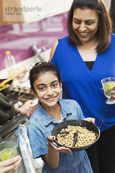 Porträt einer glücklichen indischen Mutter und Tochter bei der Zubereitung von Essen in der Küche