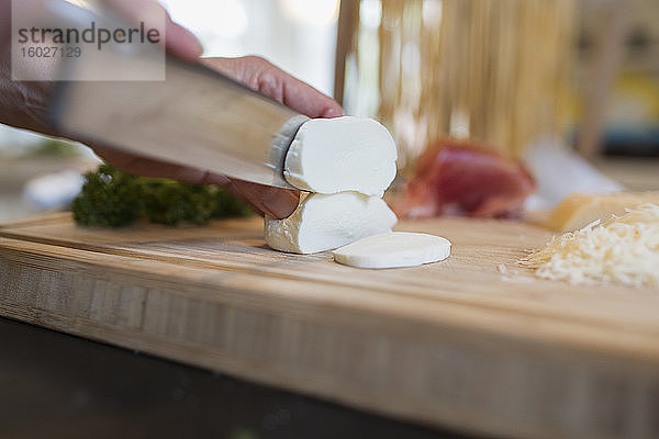 Nahaufnahme eines Messers beim Schneiden von frischem Mozzarella-Käse