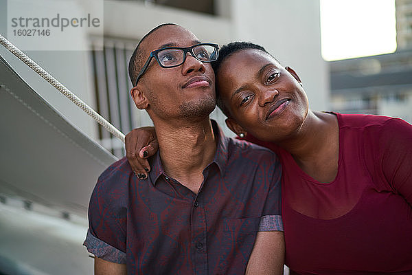 Porträt eines selbstbewussten  liebevollen jungen Paares  das sich auf der Terrasse umarmt