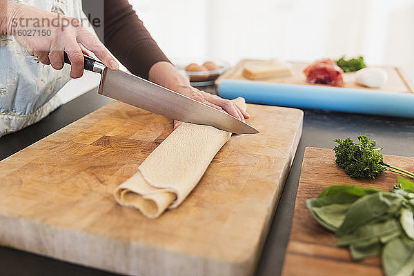 Frau schneidet frische hausgemachte Pasta auf Schneidebrett