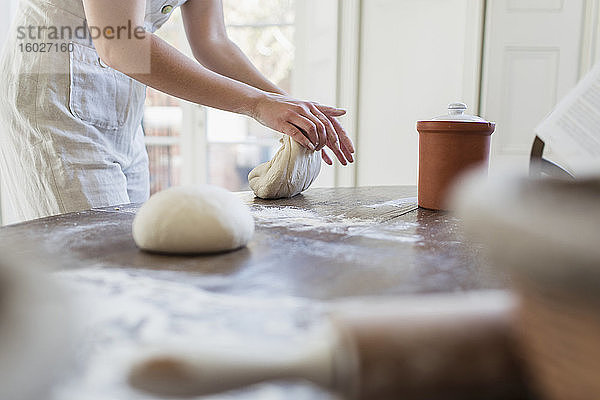 Teenager-Mädchen knetet Teig beim Backen in der Küche