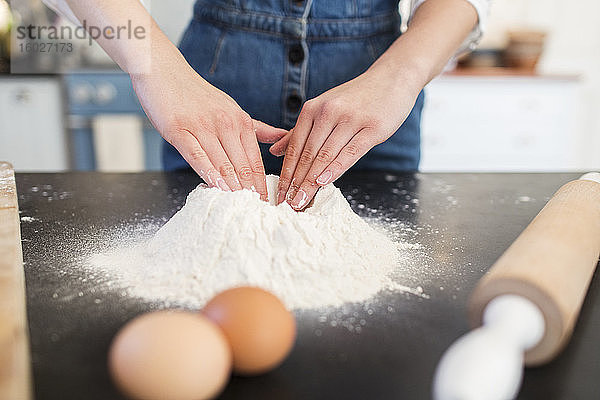 Nahaufnahme eines Teenager-Mädchens  das ein Mehlnest auf der Küchentheke baut