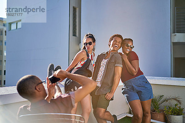 Verspielte junge Freunde posieren für ein Foto auf einem sonnigen städtischen Balkon