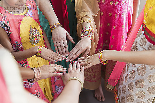 Indische Frauen in Saris reichen sich im Kreis die Hände