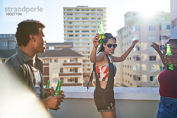 Unbeschwerte junge Freunde tanzen auf dem sonnigen städtischen Dachbalkon