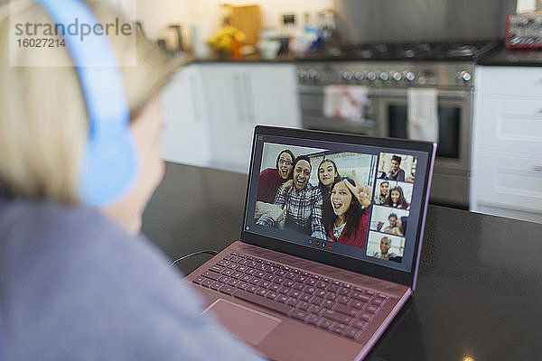 Frau mit Laptop im Video-Chat mit Freunden in der Küche