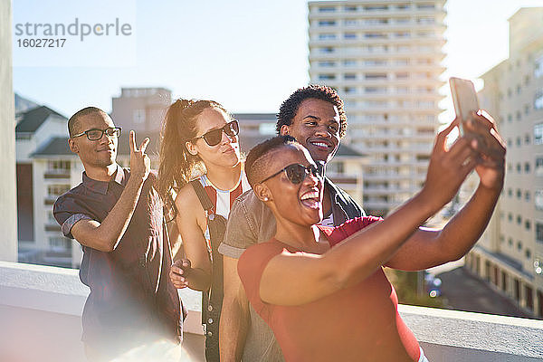 Junge Freunde nutzen Smartphone auf sonnigem städtischen Dachbalkon