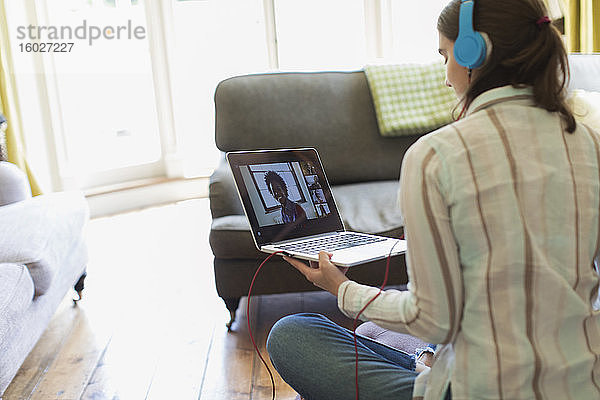 Teenager-Mädchen mit Kopfhörern und Laptop im Video-Chat mit Freunden