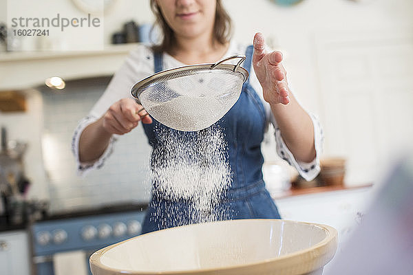 Teenager-Mädchen sieben Mehl in der Küche