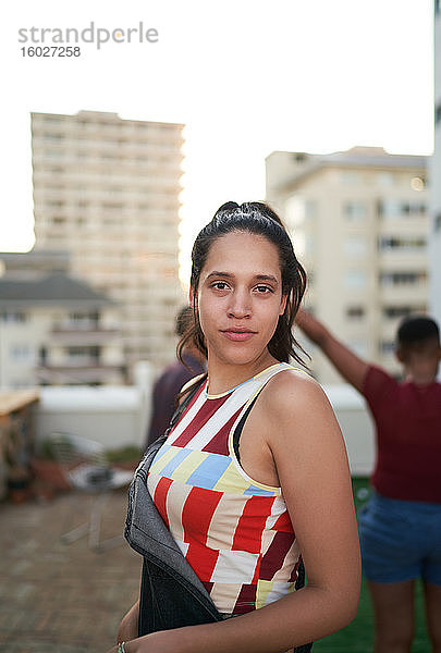 Porträt selbstbewusste junge Frau auf städtischem Dachbalkon