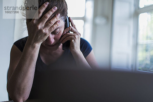 Frustrierte Frau telefoniert am Laptop