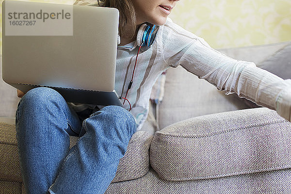 Teenagerin mit Laptop auf dem Sofa