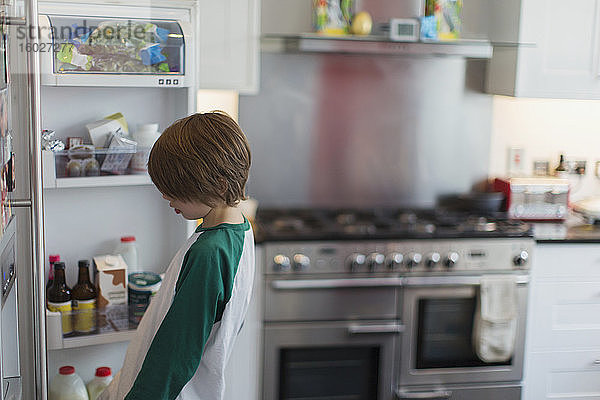 Junge schaut in Küchenkühlschrank