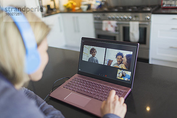 Frau mit Kopfhörern und Laptop im Video-Chat mit Freunden