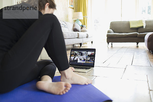Frau nimmt am Online-Yoga-Kurs am Laptop teil