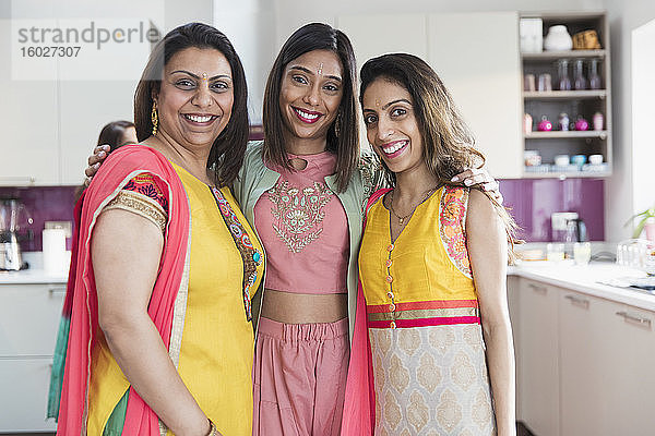 Porträt glücklicher indischer Schwestern in Saris in der Küche