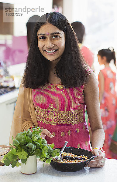 Porträt lächelndes indisches Mädchen in Sari beim Essen in der Küche