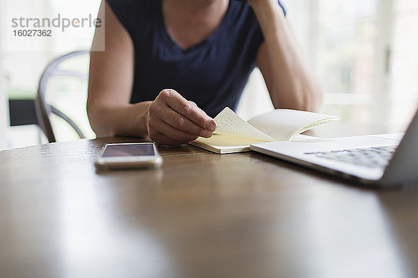 Frau mit Notebook arbeitet von zu Hause am Laptop